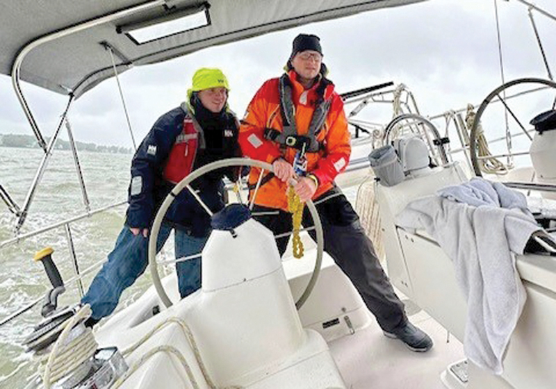 two men at helm of a sailboat