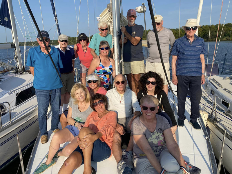 Singles on Sailboats sailing club members on foredeck of sailboat