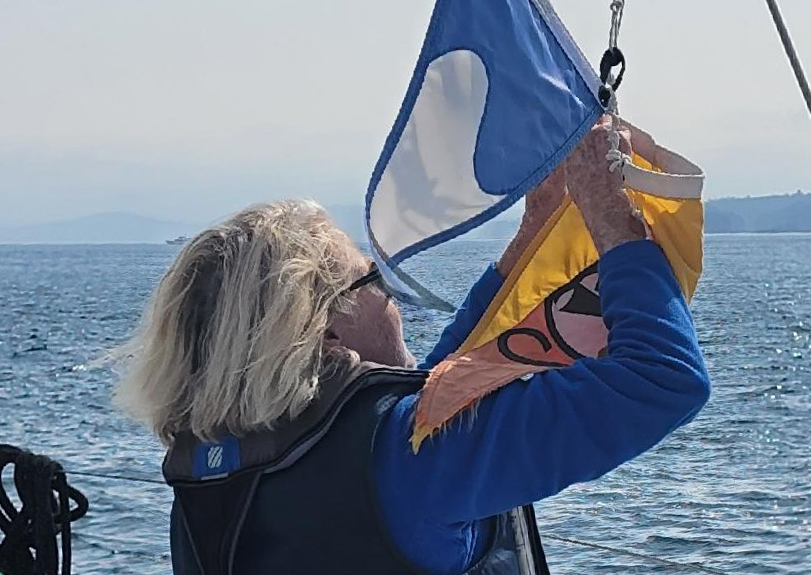 woman hosting burgee while sailing