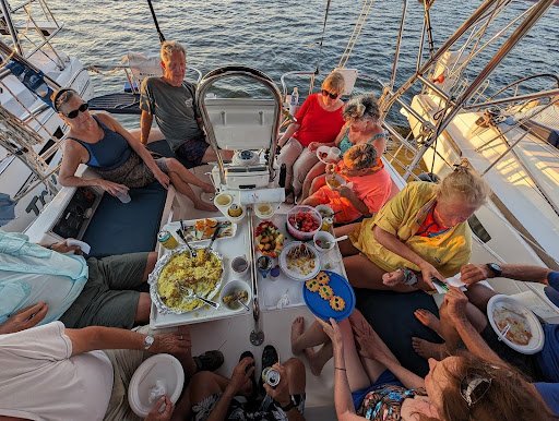 Members of The Sailing Club Inc share a meal on a sailboat