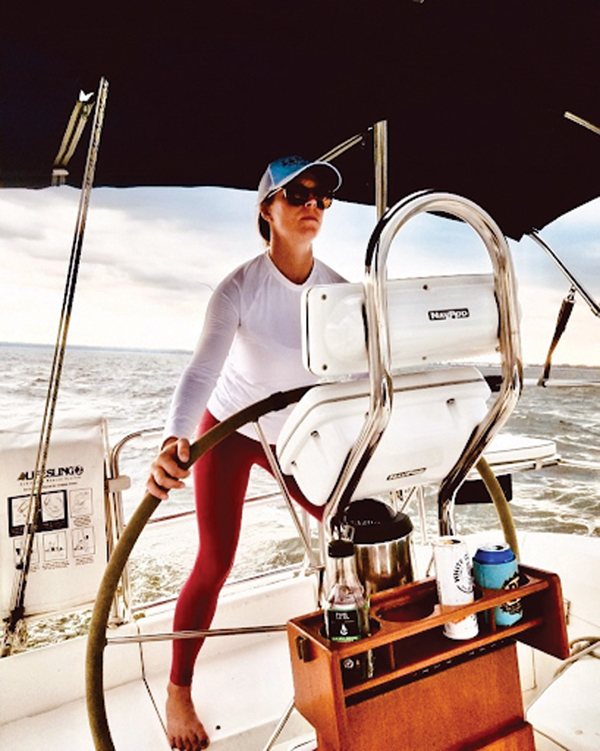 woman steering sailboat while standing